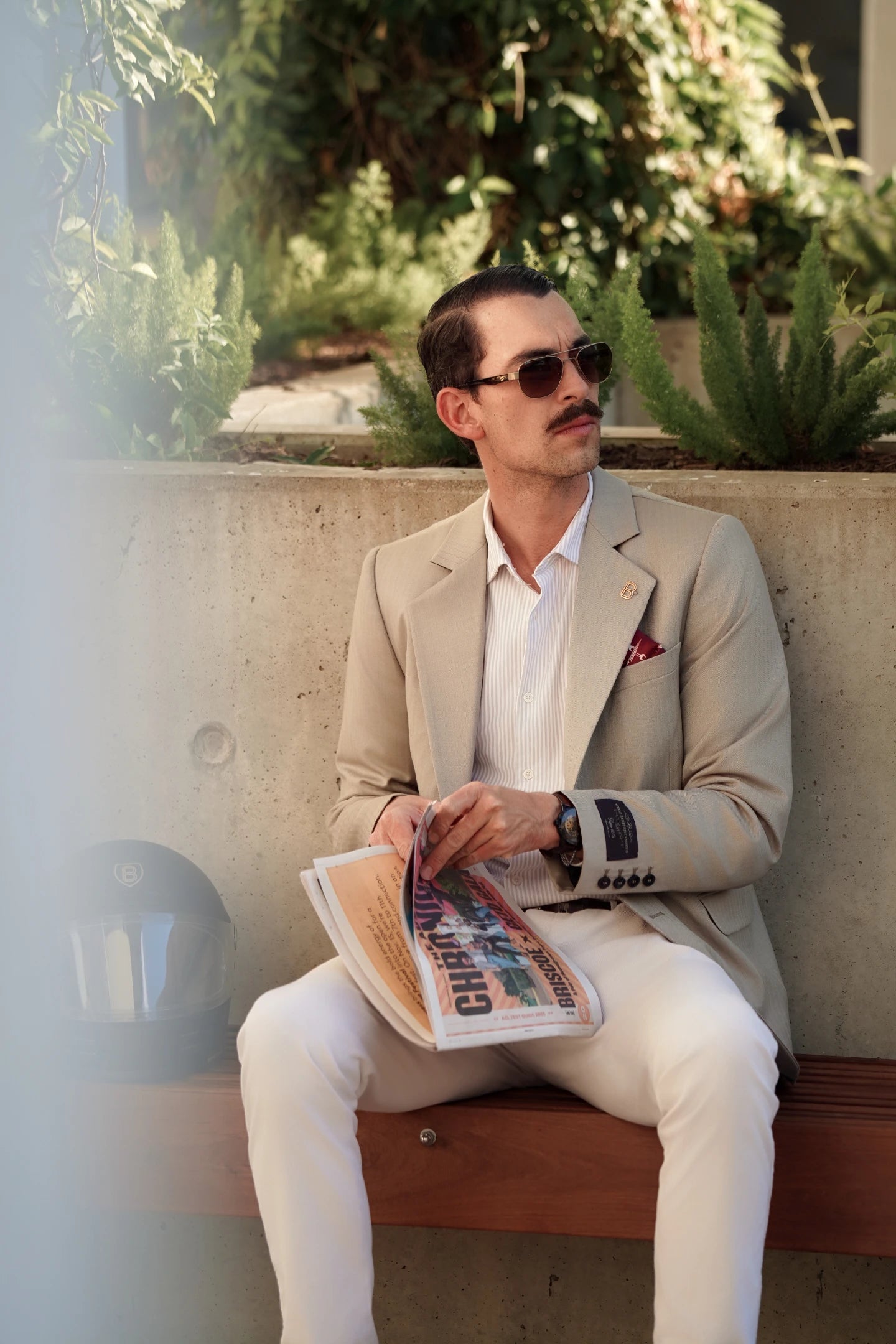 Man wearing the Brummell x DGR Limited Edition blazer while seated outdoors, pairing the motorcycle blazer with a striped shirt and white trousers.