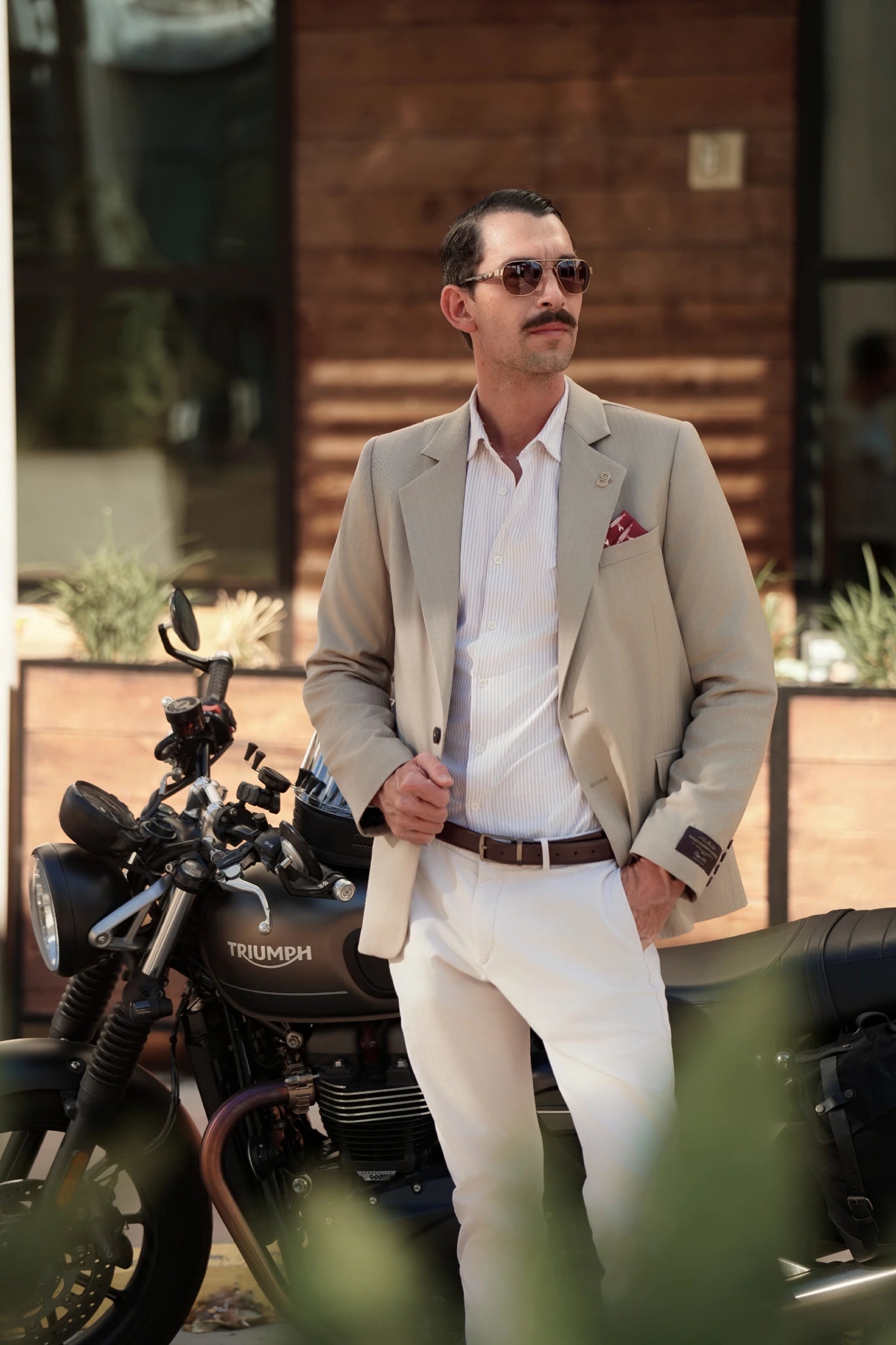 Model wearing the Brummell x DGR Limited Edition motorcycle blazer while standing beside a Triumph motorcycle, blending luxury tailoring with motorcycle culture.
